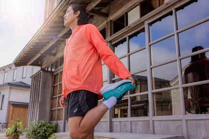 Person stretching wearing Asics running shoes