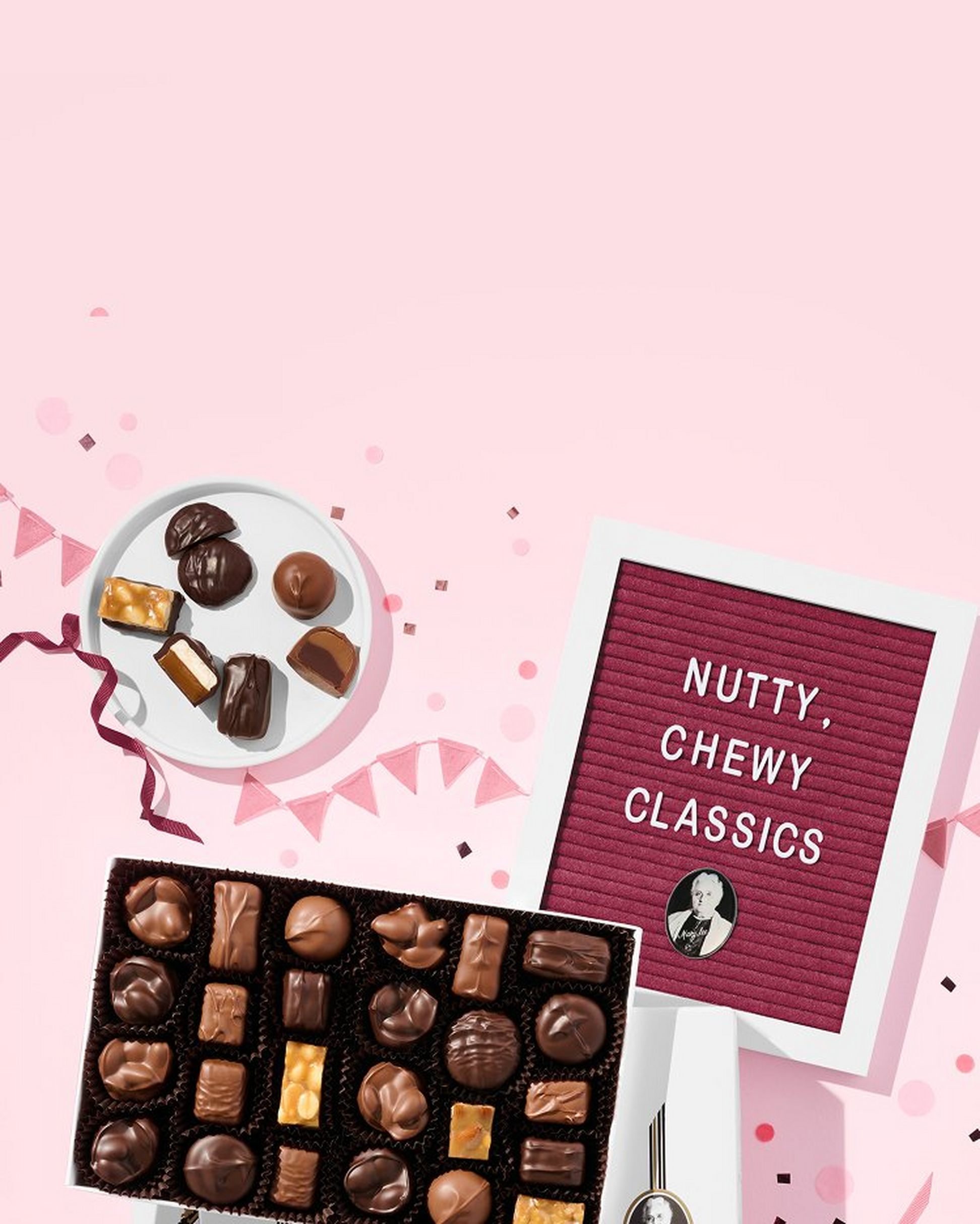 A frame that reads "Nutty, Chewy Classics" next to a box and plate of chocolates on a pink background.