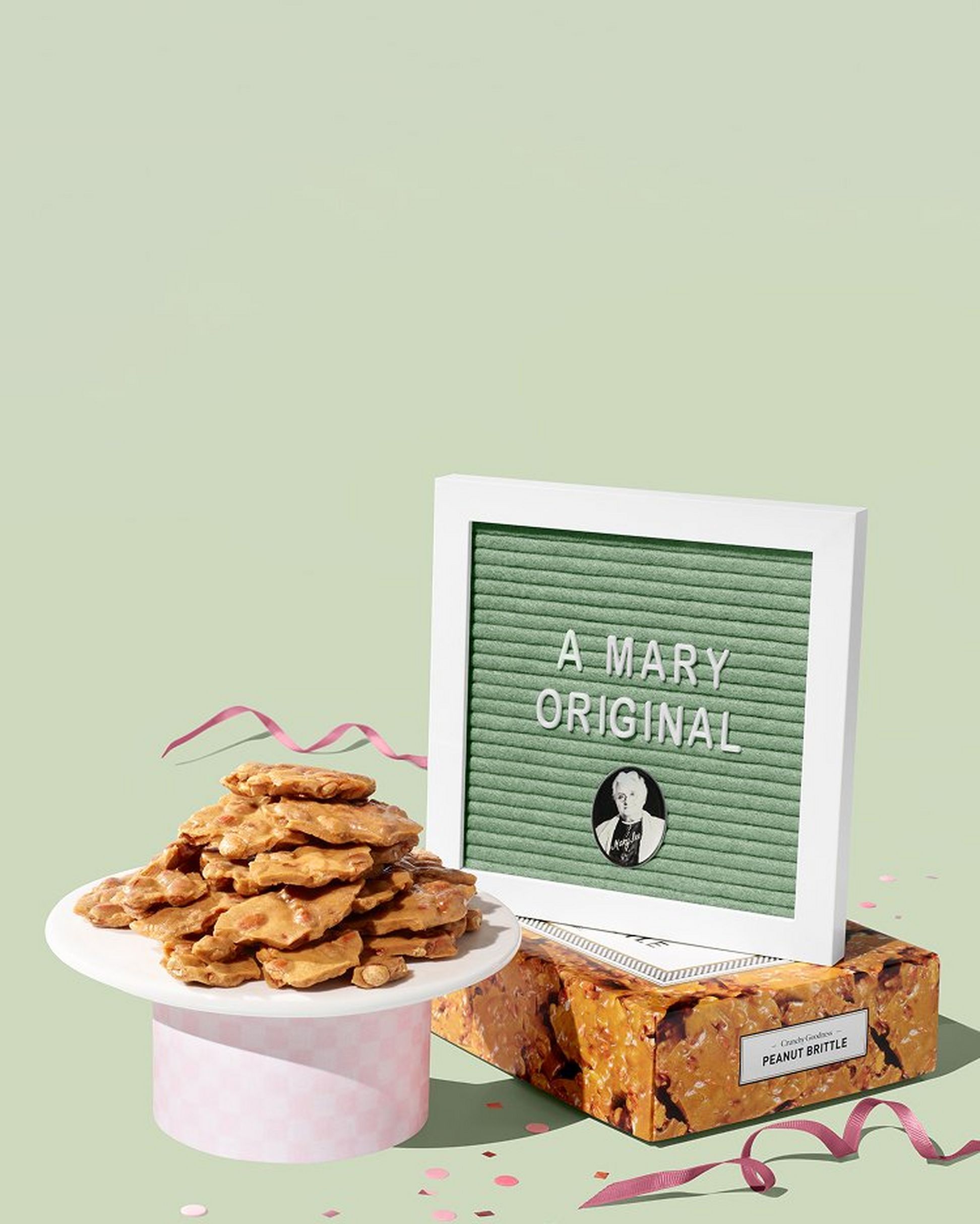 Frame that reads "A Mary Original" with a stack of peanut brittle on a pastel green background. 