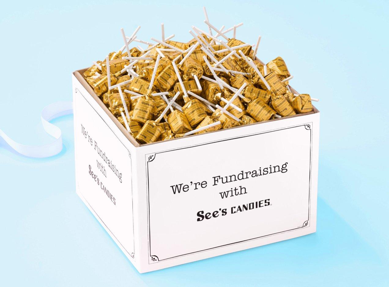 A box of bulk lollypops that says "We're Fundraising with See's Candies"