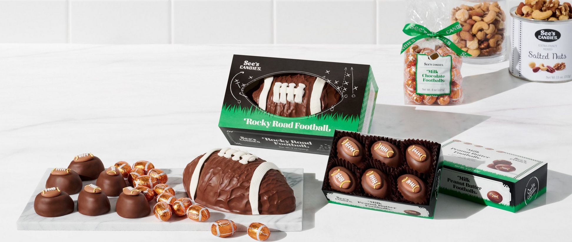 See's Candies rocky road football next to a tray of chocolate peanut butter footballs and milk foil footballs