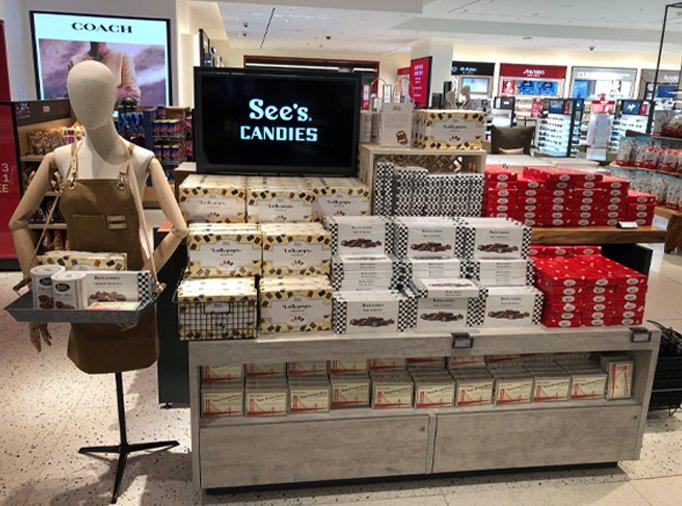 A stack of boxed chocolates and candies sits on a display case in a retail shop.