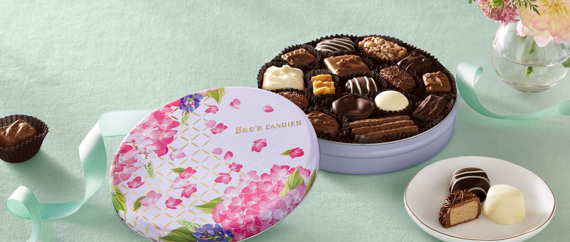 A purple tin decorated with pink flowers filled with chocolates