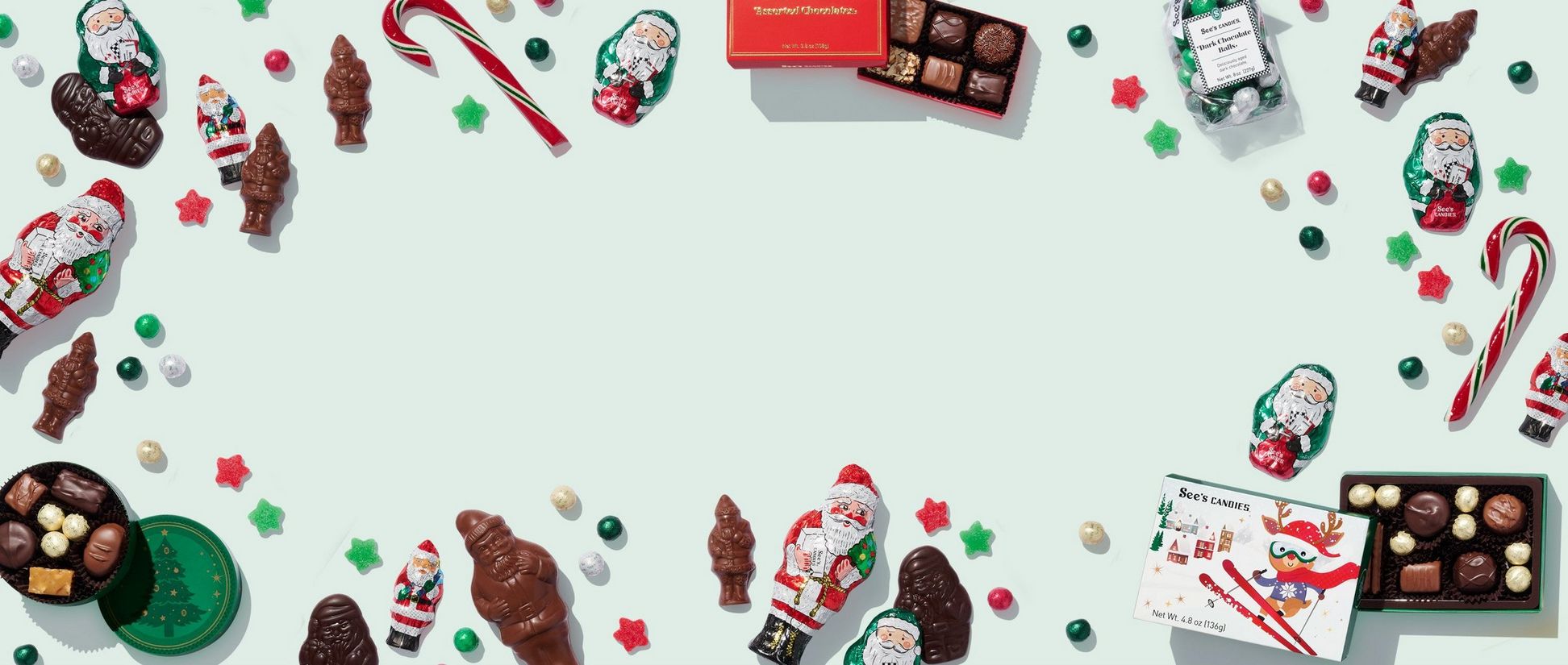 A border of chocolates and candies including chocolate santas, candy canes and sour stars