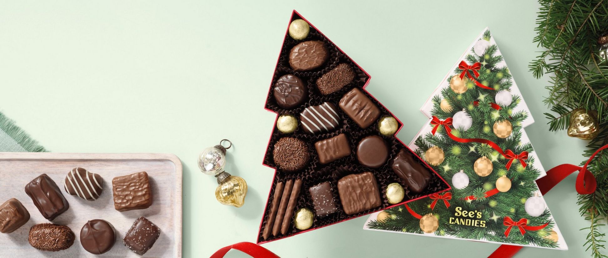 Open box of See's Candies Christmas Tree Assorted box on a green background.