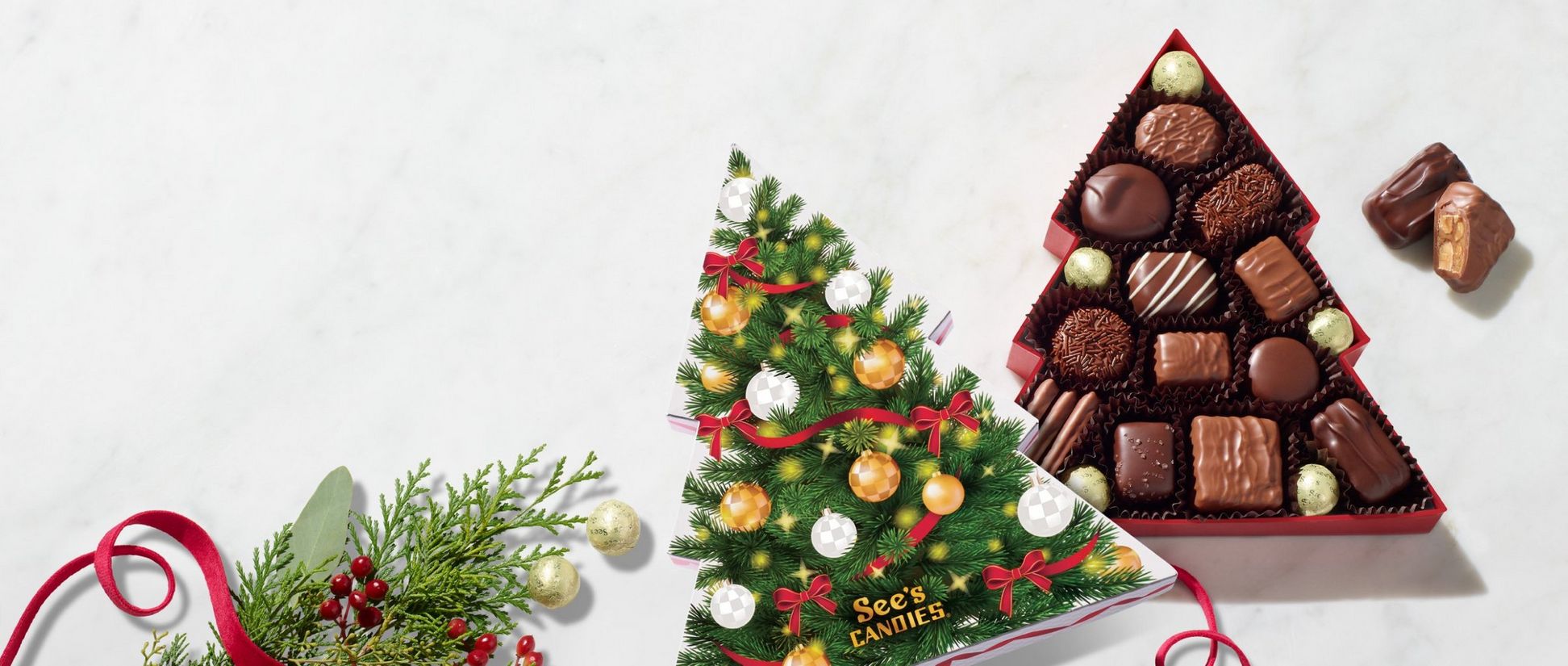 A Christmas tree shaped box of chocolates is displayed with milk and dark chocolates inside. The box is decorated with a Christmas tree.