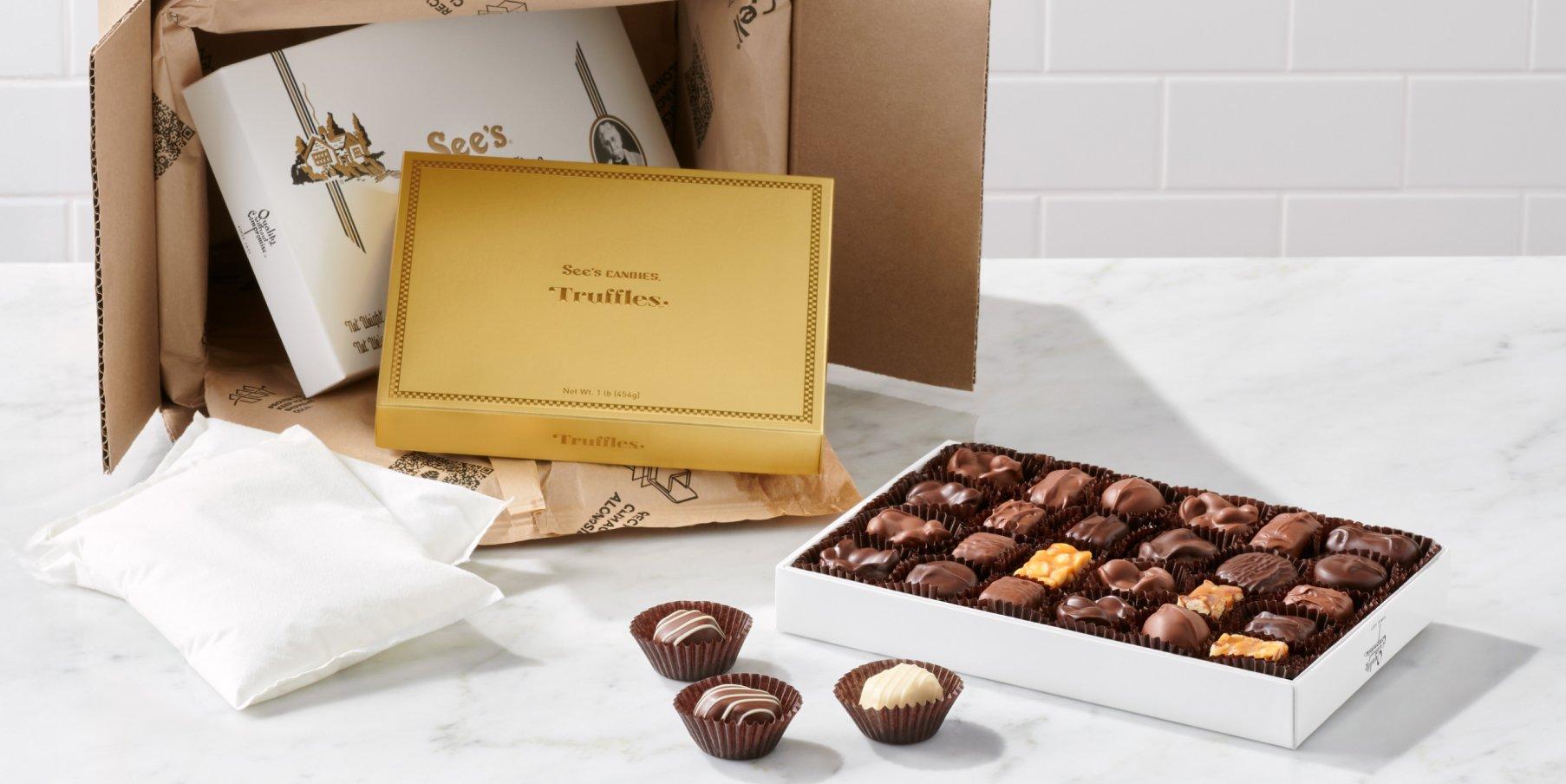 An open box of assorted chocolates next to a box of truffles coming out of a an insulated shipping box