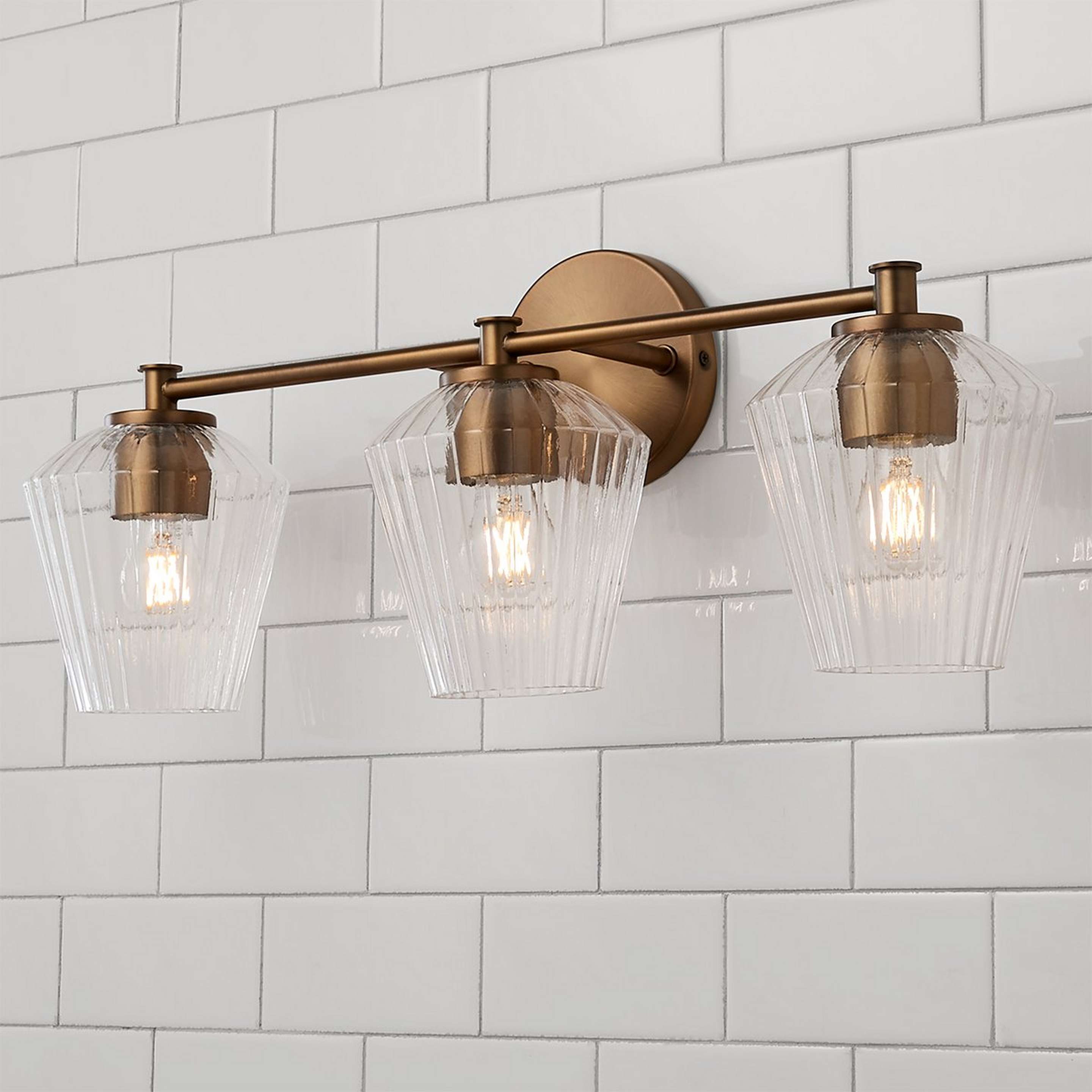 A Fluted Felix Vanity Light - 3 Light with Aged Brass / Clear Fluted Glass color