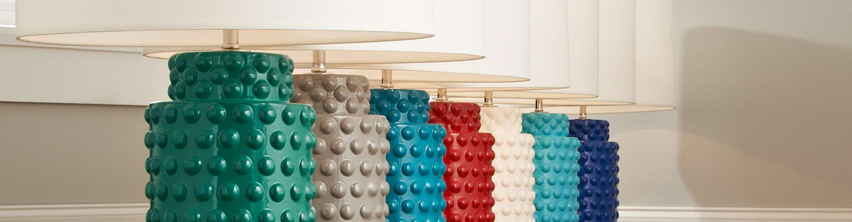 Line of colorful table lamps with white shades
