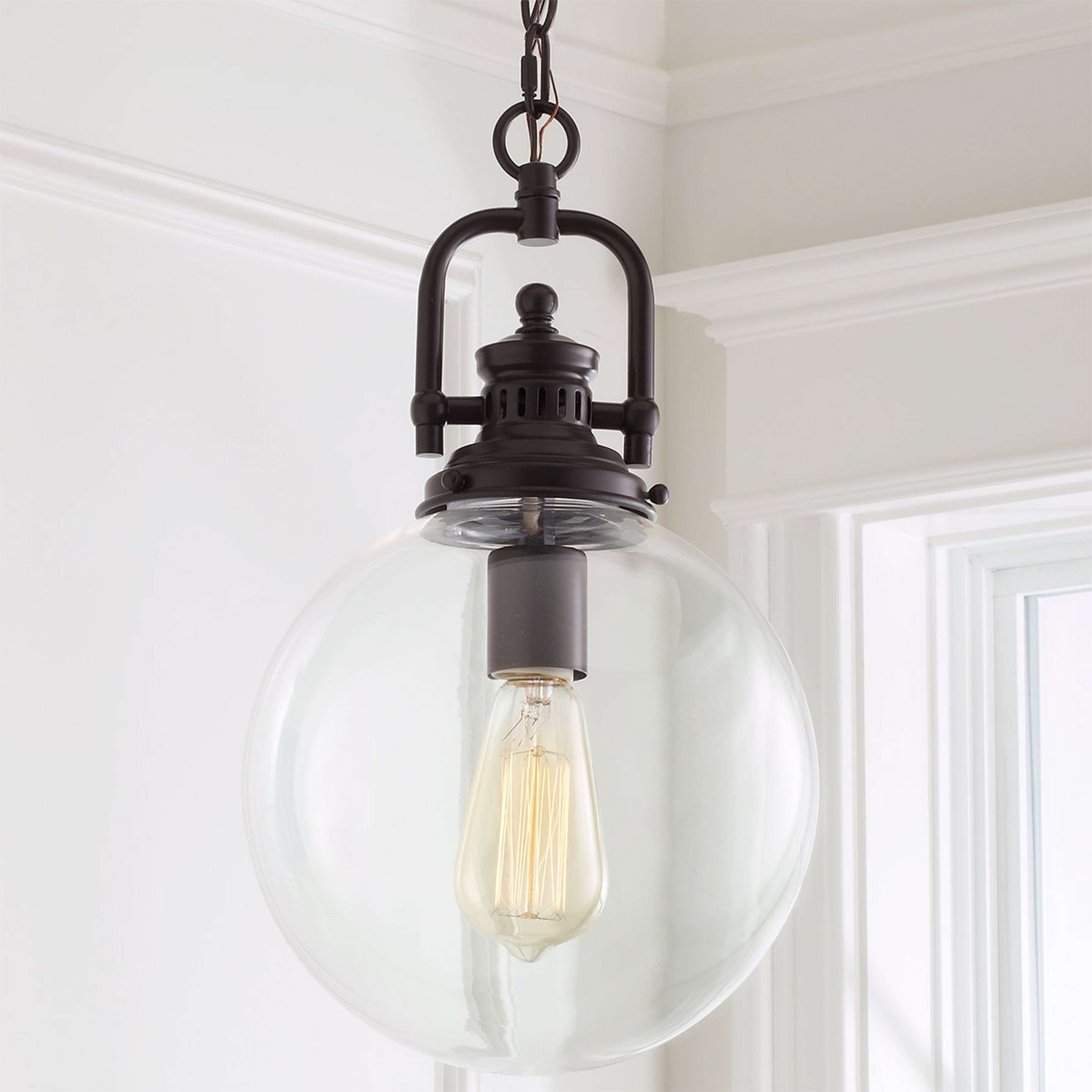 A Clear Glass Globe Industrial Pendant with Bronze color