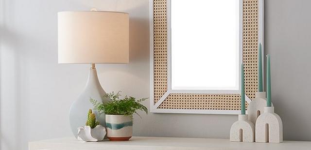 Blue table lamp beside rattan mirror