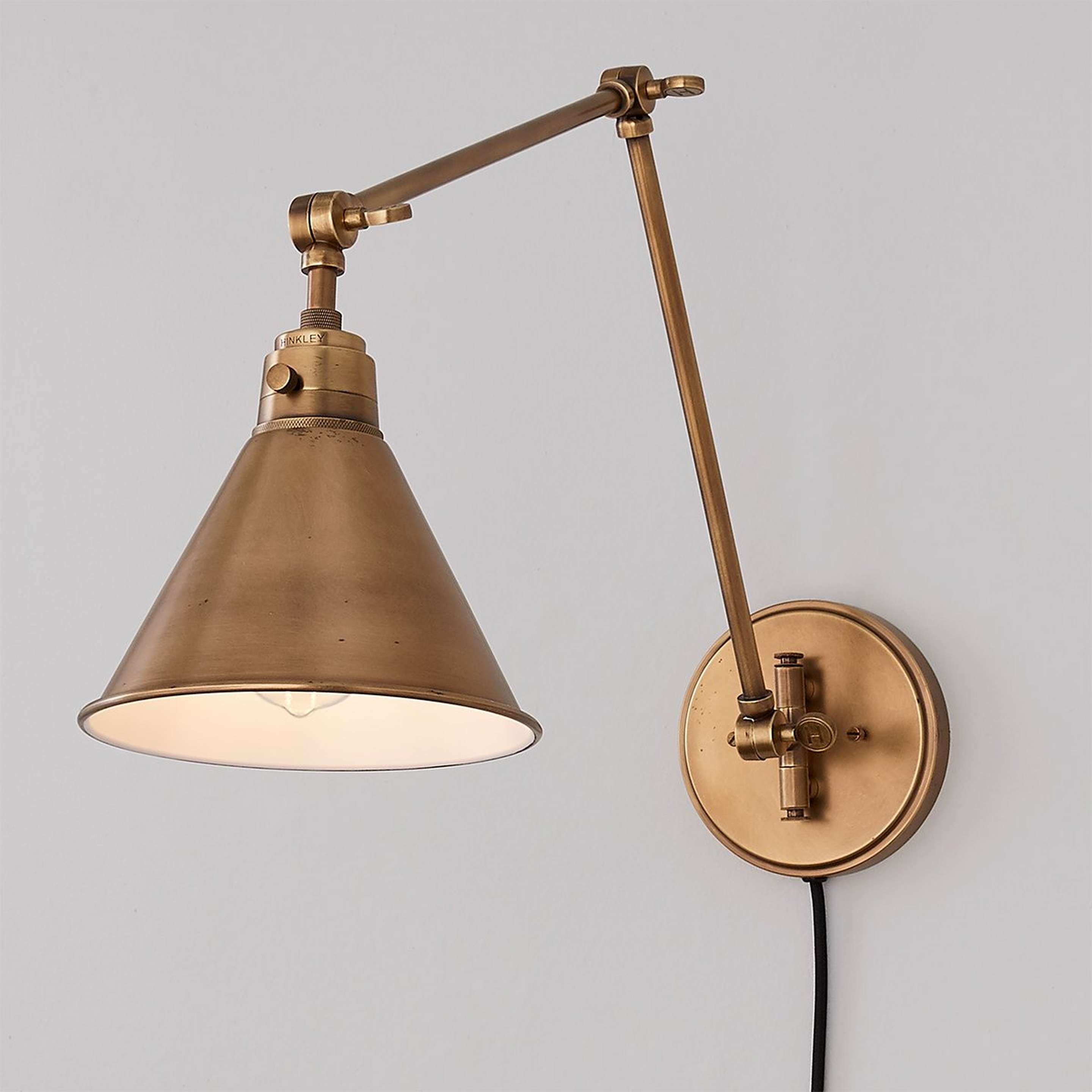 A Cyrus Arched Swing Arm Sconce - Metal Shade with Aged Brass color