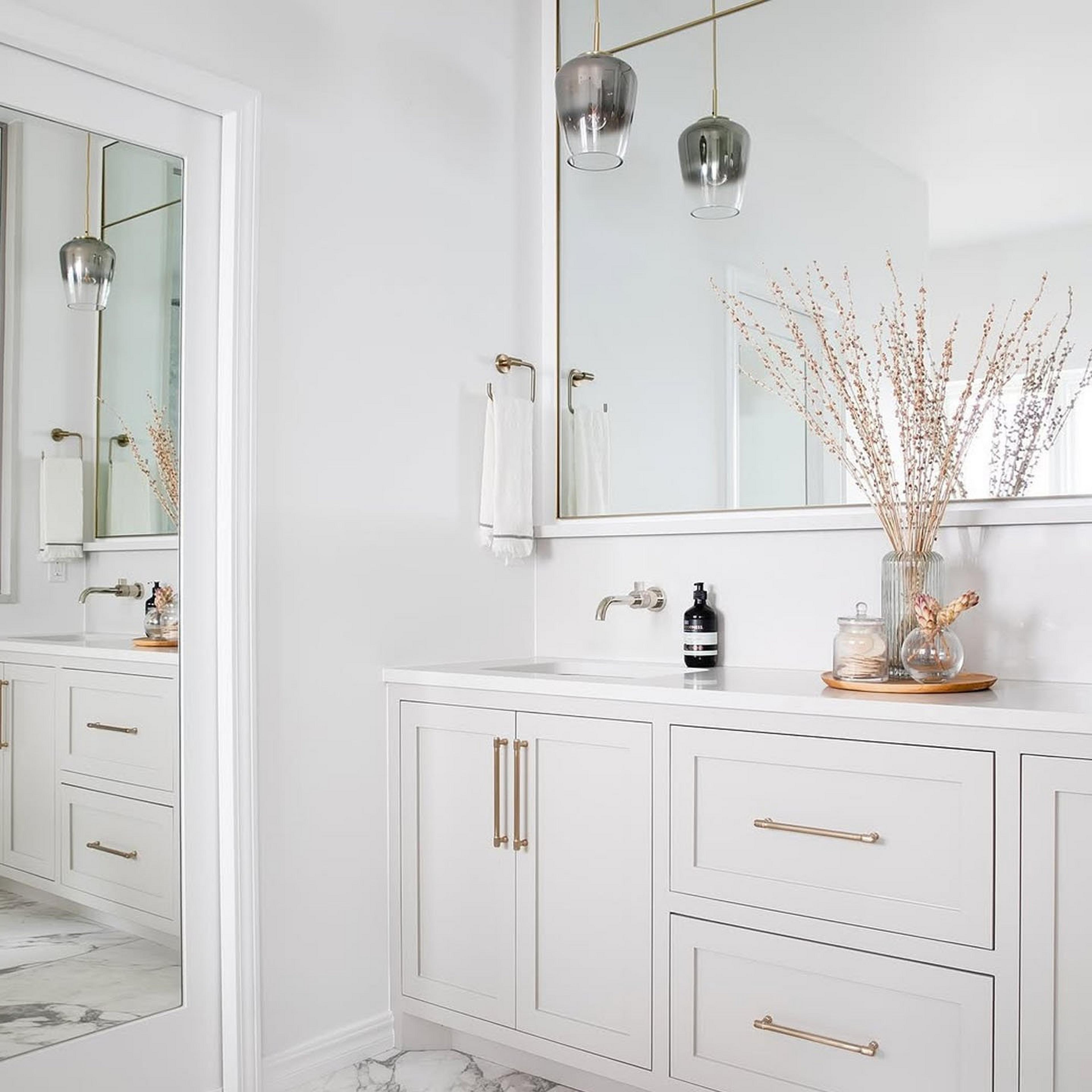 Mirror cone pendant hanging over a vanity in an all white bathroom