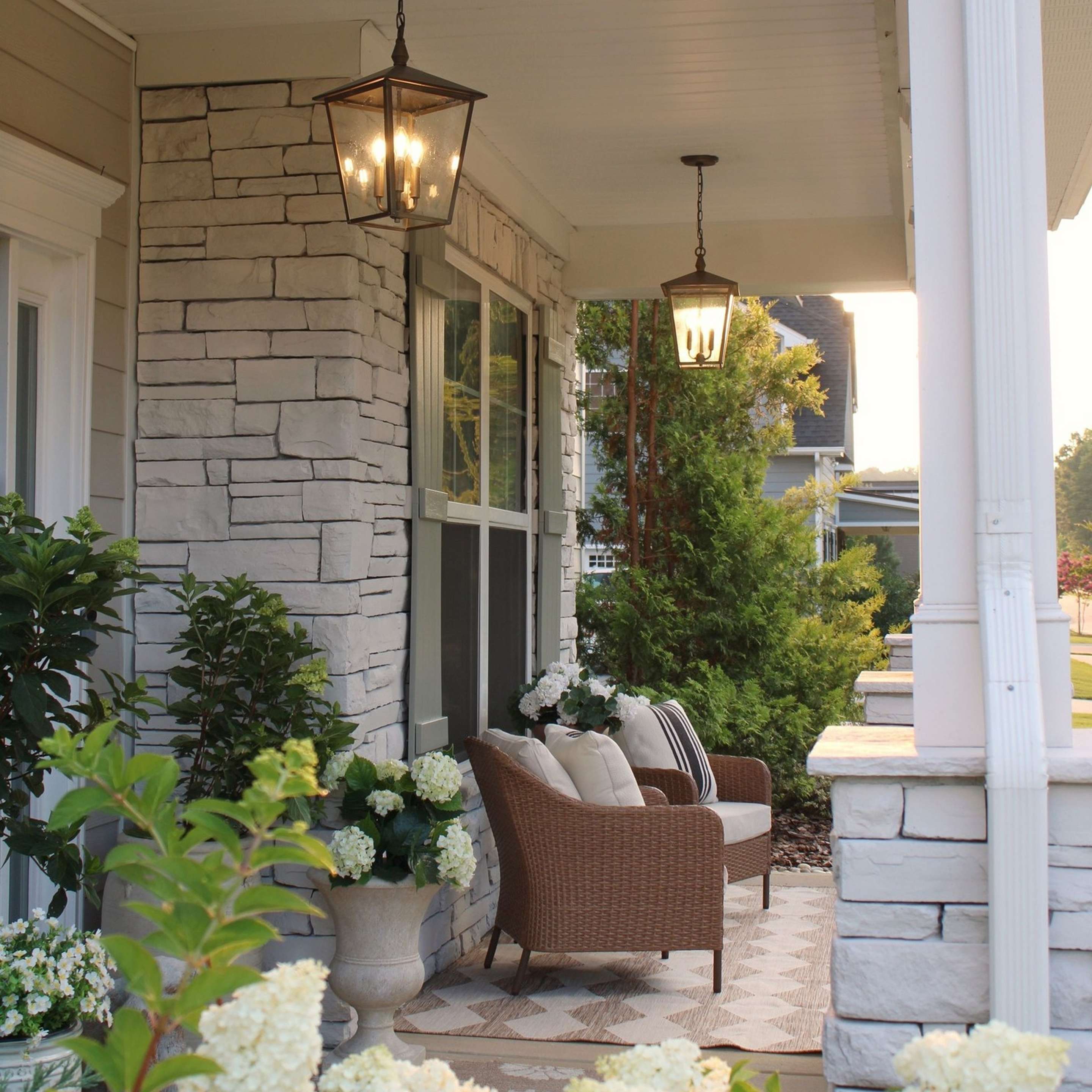 Two Burnished Bronze Classic Caroline Outdoor Hanging Lanterns on a porch