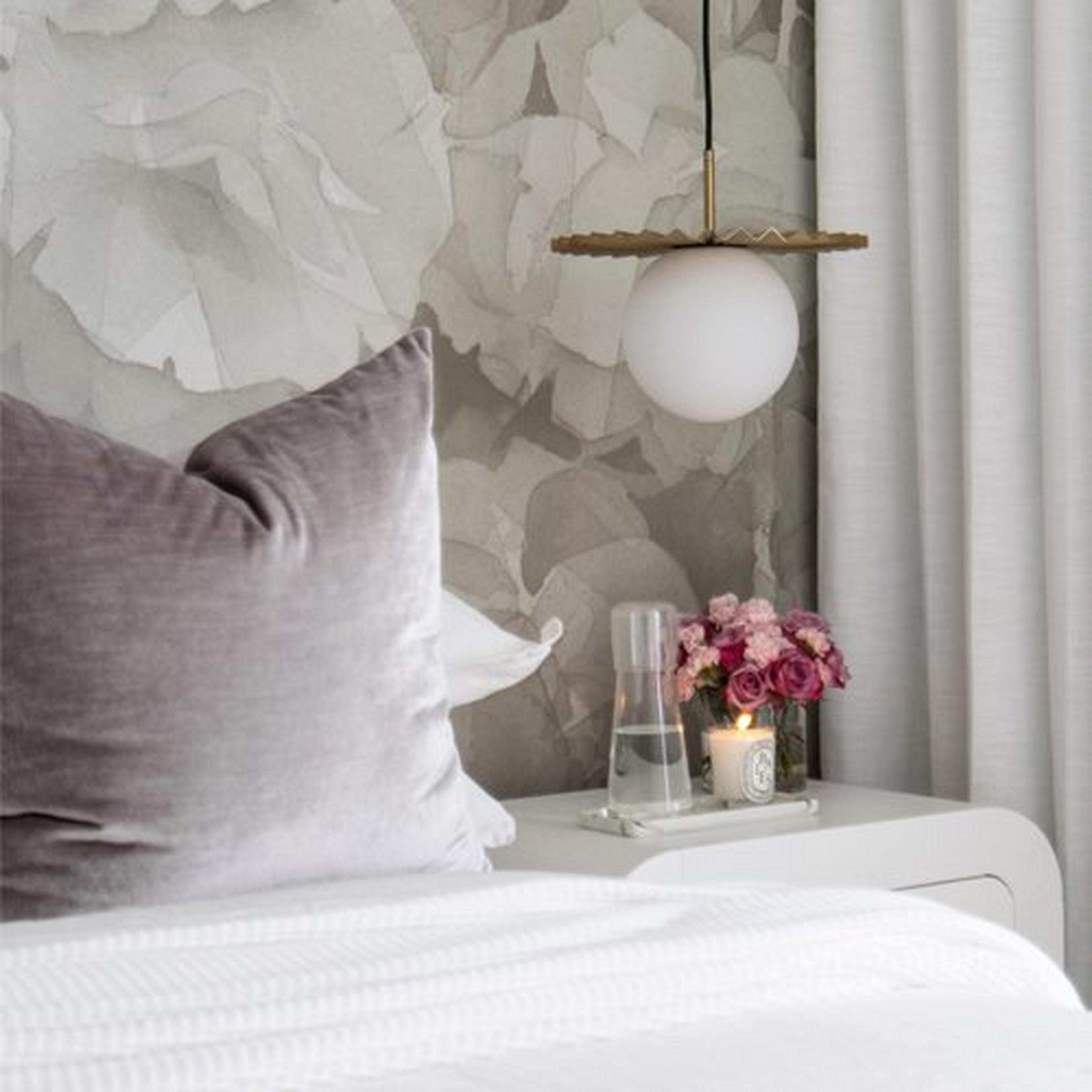 Brushed gold En Pointe pendant hanging over a bedside nightstand
