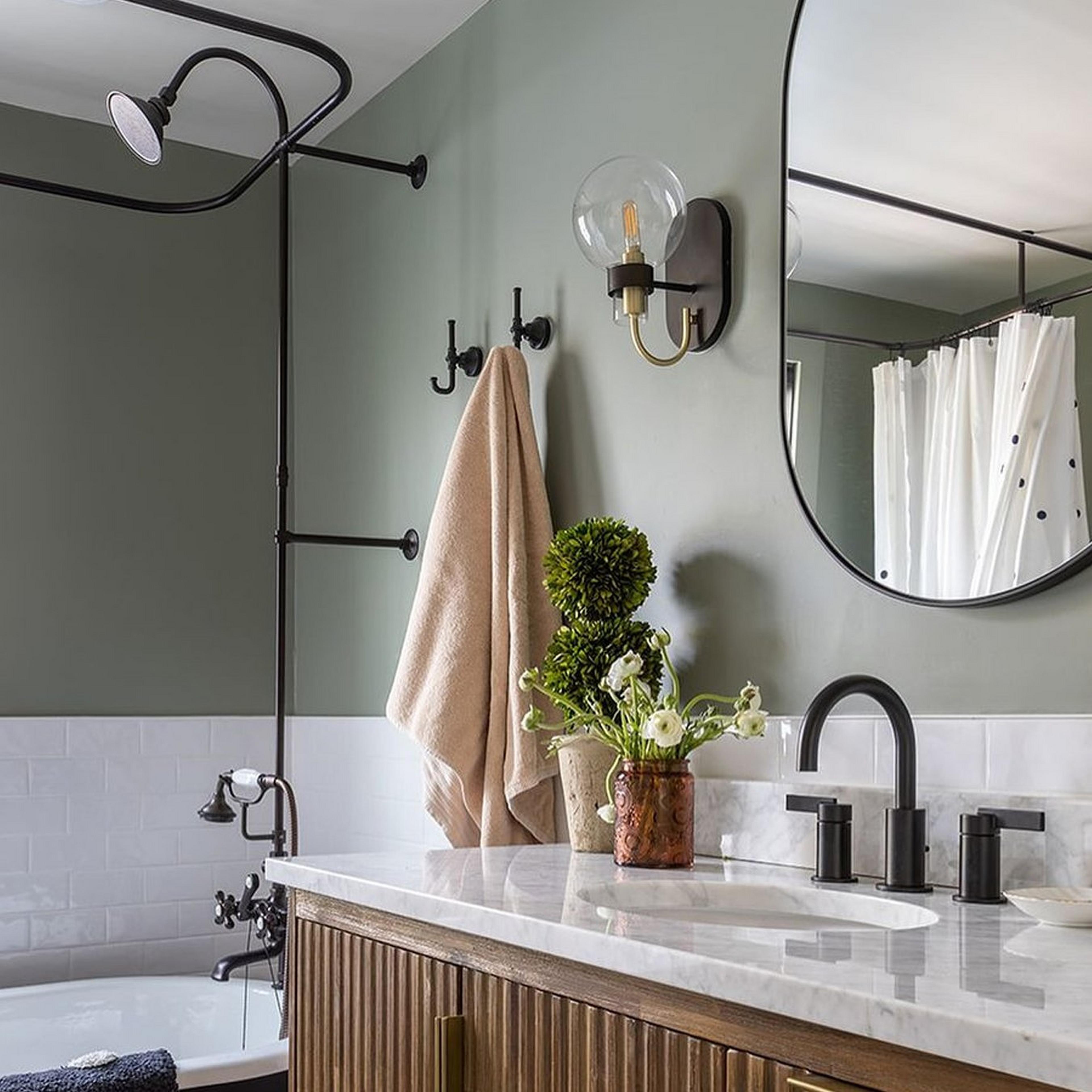 Bronze and satin brass  in a bathroom with sage walls and an oval mirror