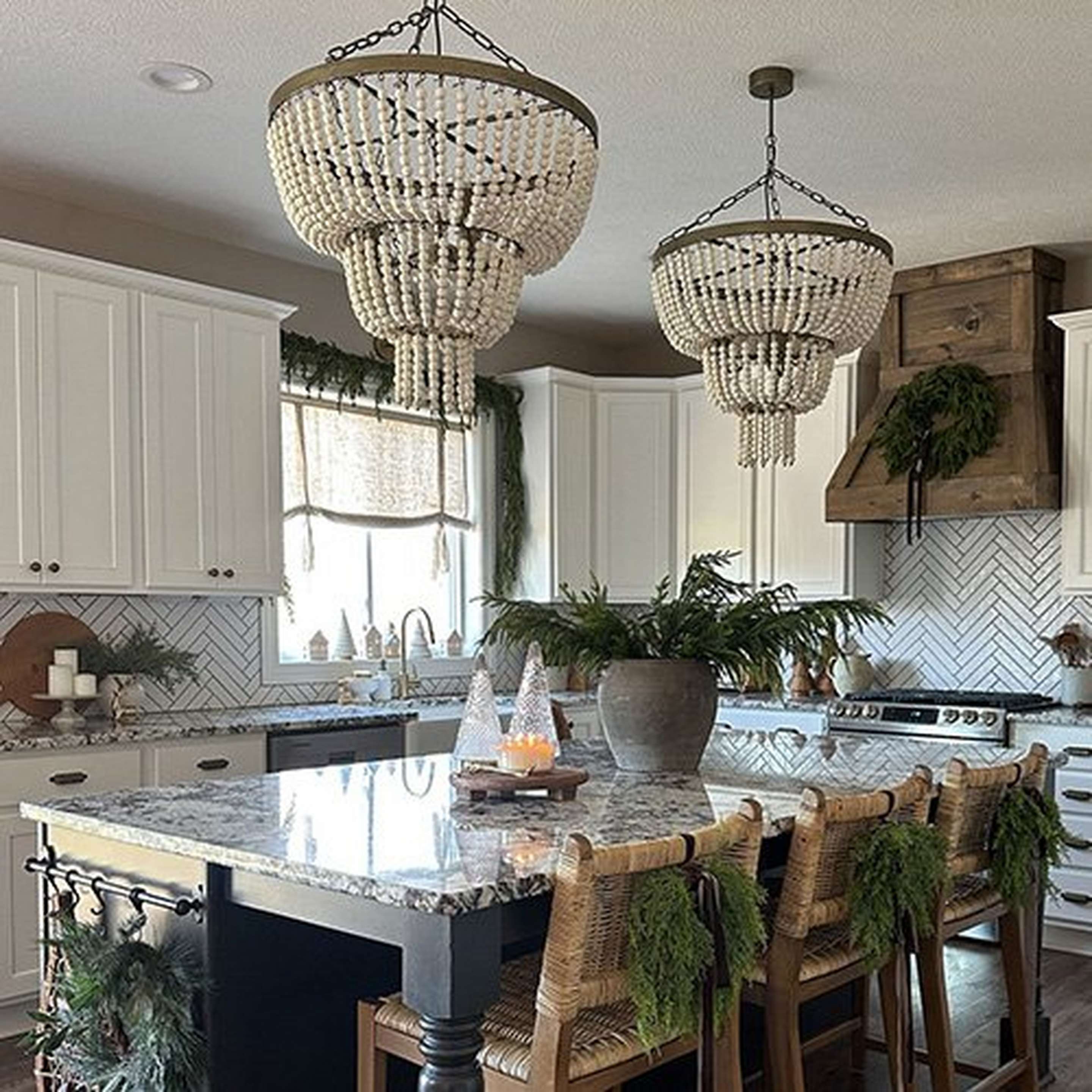 Two beaded chandeliers over a holiday decorated kitchen island