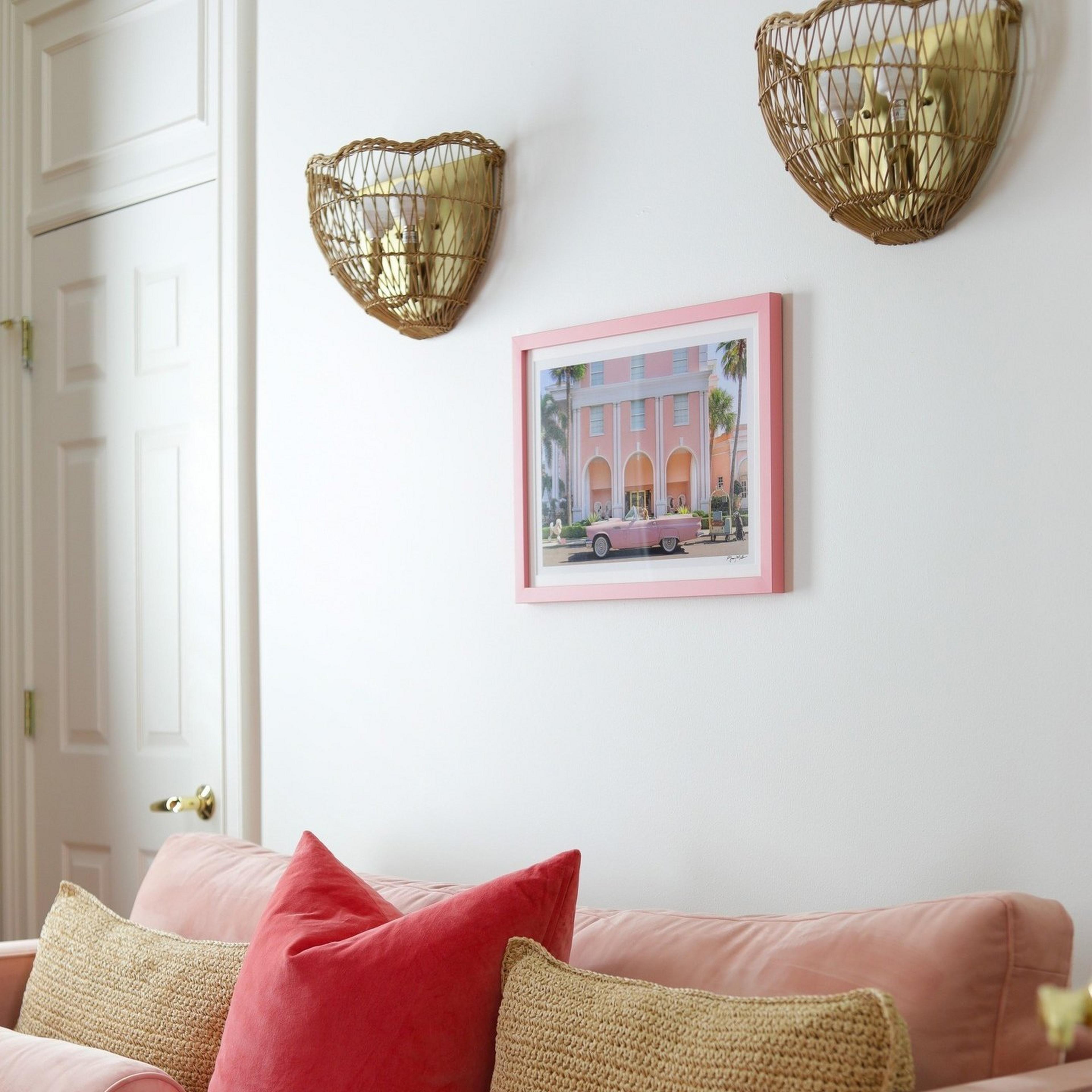 Two scalloped rattan sconces over a pink couch