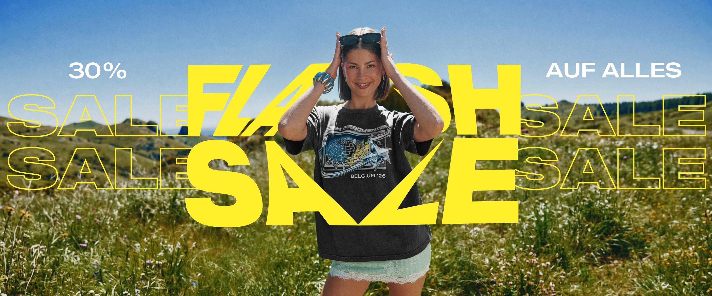 Mit bedrucktem T-Shirt und Sonnenbrille steht eine lächelnde Frau auf einer Wiese mit dem Werbetext 30% auf alles, Flash Sale.