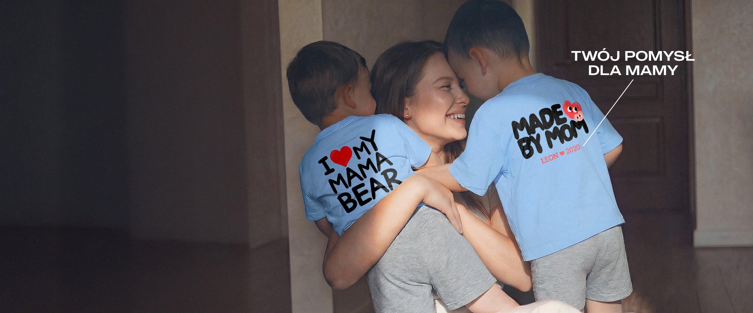 Uśmiechnięta mama trzyma w ramionach dwoje małych dzieci; oboje mają na sobie niebieskie koszulki z motywami na Dzień Matki i spersonalizowanymi nadrukami.