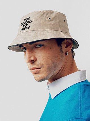 Homme portant un bob beige avec l’impression noire « Vos idées, vos envies », photographié de profil.