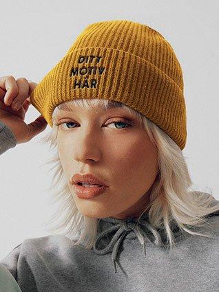 Person bärar mörkblå tygpåse, mitt på vitt tryck "Ditt motiv här".