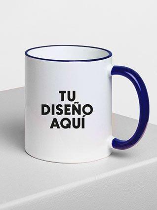 Taza blanca con borde y asa azules, con la frase "TU DISEÑO AQUÍ" impresa en el frente