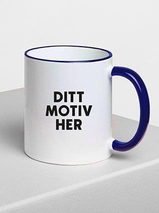 Hvit keramikkopp med blå hank, svart påtrykk «Ditt Motiv her» på forsiden.
