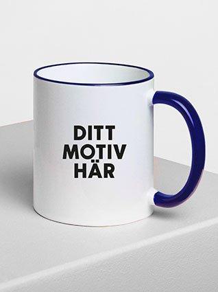 Hvit keramikkopp med blå hank, svart påtrykk «Ditt Motiv her» på forsiden.