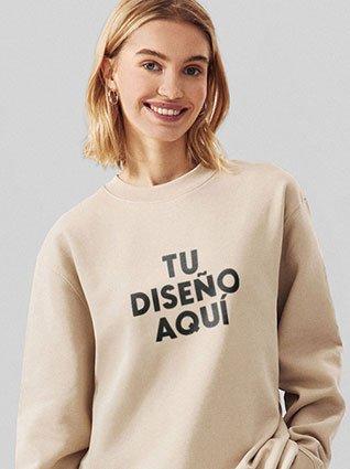 Mujer de cabello rubio usando sudadera beige con la frase "TU DISEÑO AQUÍ" impresa en el frente