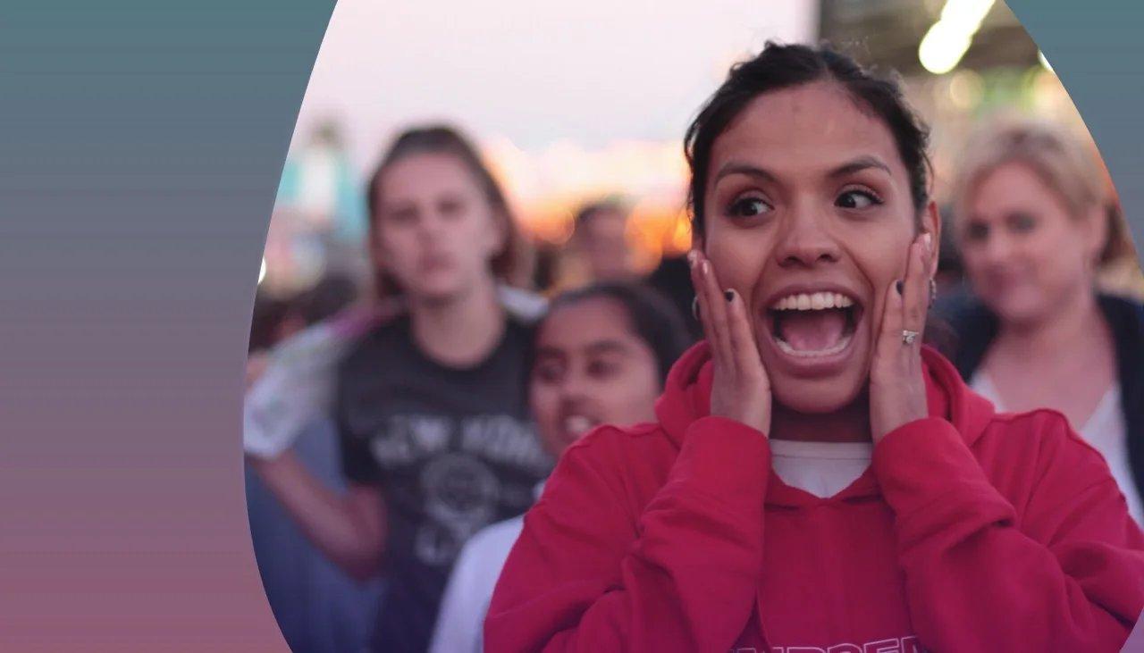 Vor Freude und begeisterung schreiende junge Frau und weitere Fans hinter ihr.