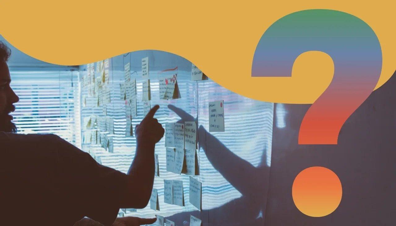 Person zeigt auf Klebezettel an einem Whiteboard.