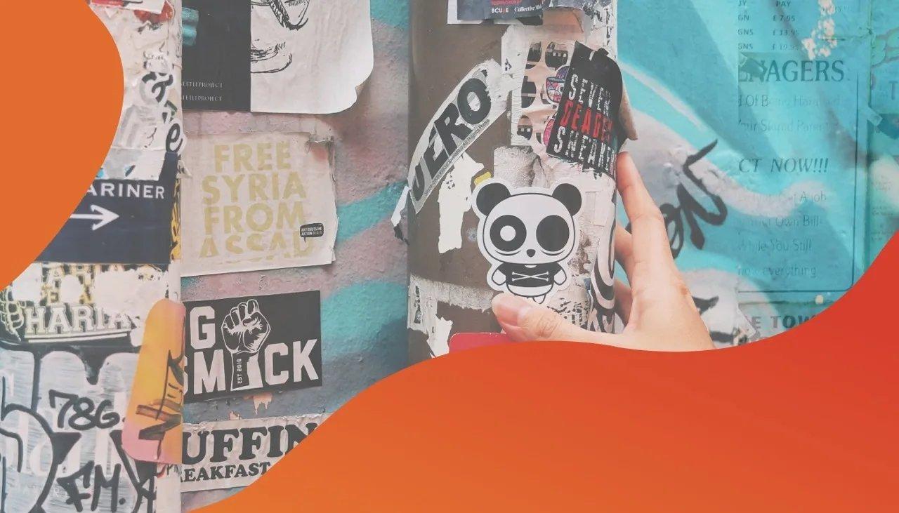 Detail diverser Sticker, die auf Ampel und Hauswand geklebt sind.