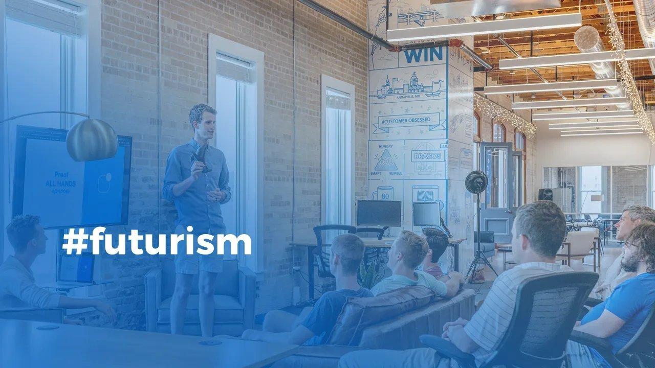 Mann steht in Vortragshalle auf einer kleinen Bühne und hält einen Vortrag, dazu der Hashtag futurism.