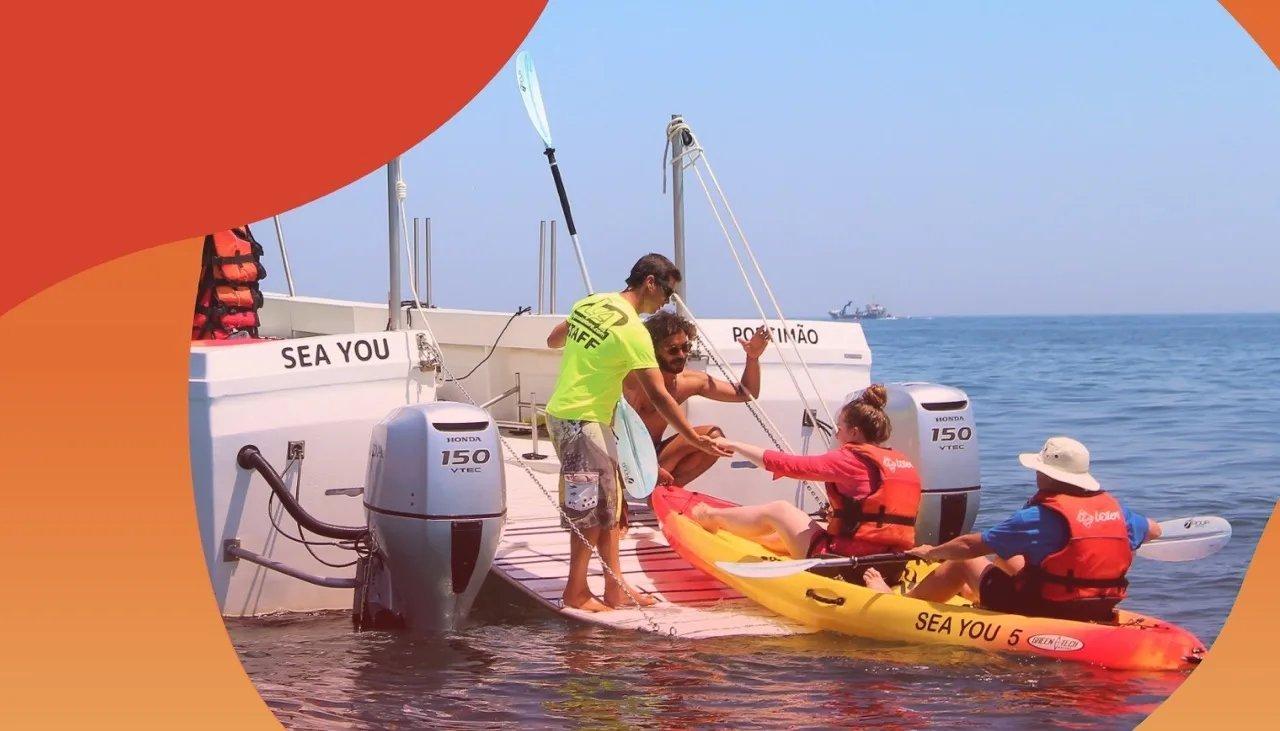 Zwei Personen im Kajak legen an einem Steg an und bekommen Hilfe von weiterer Person am Land.