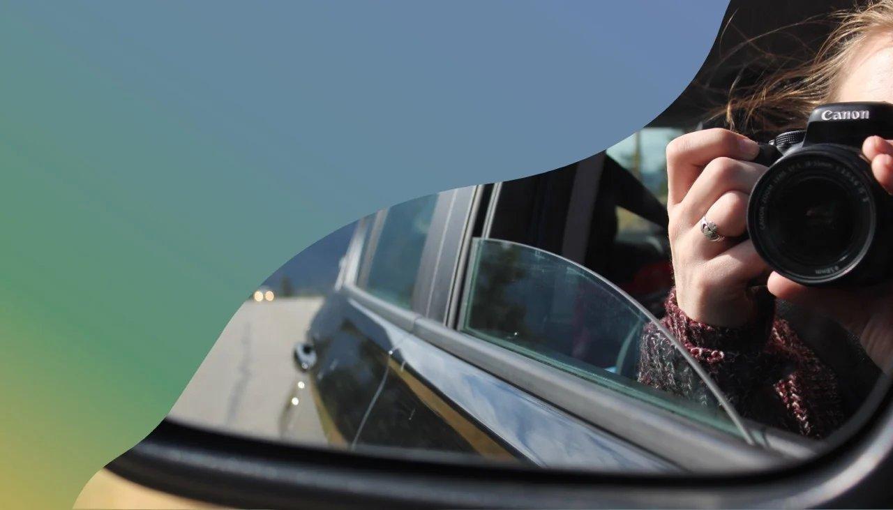Person auf dem Beifahrersitz schießt ein Foto bei geöffnetem Fenster.