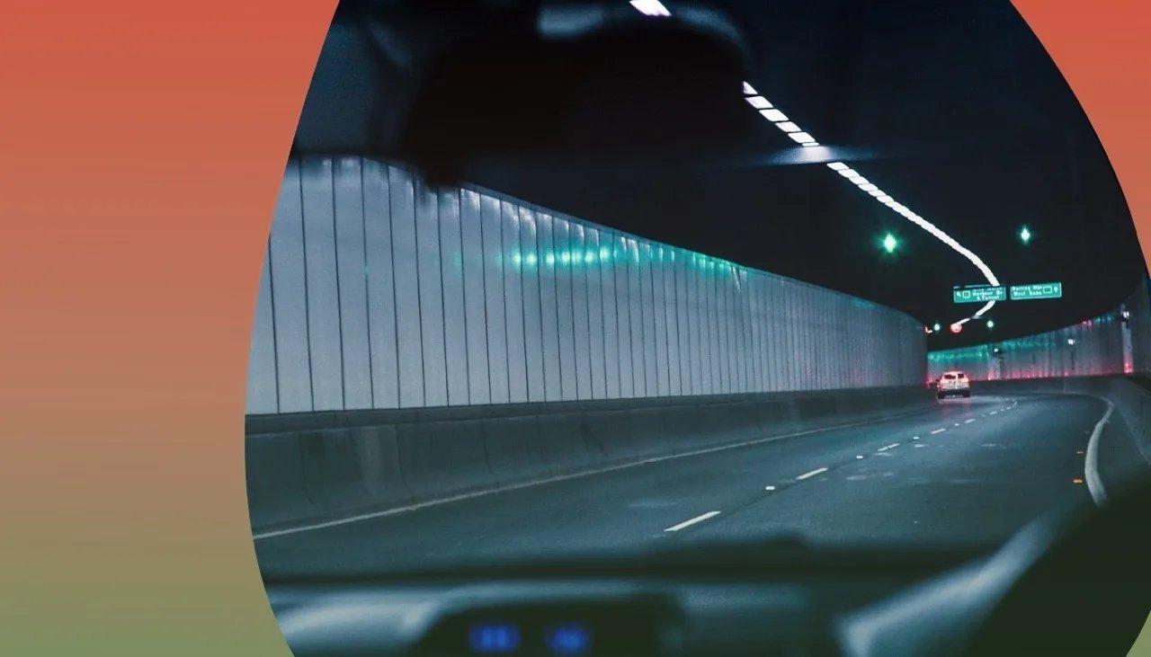 Durch die Frontscheibe sieht man bunte Lichter in einem Tunnel.