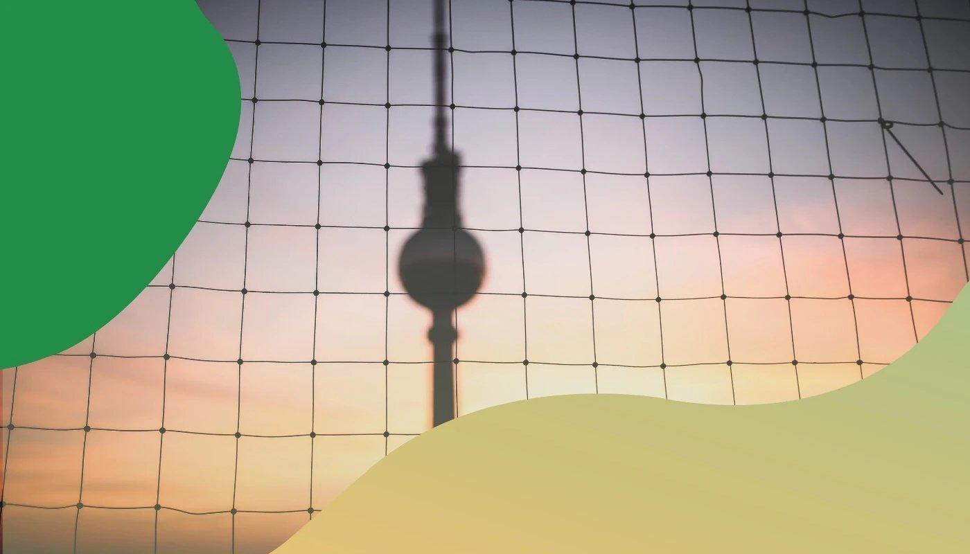 Berliner Fernsehturm unscharf hinter einem Volleyballnetz bei Sonnenuntergang, grafisch eingerahmt mit grün-gelbem Verlauf.