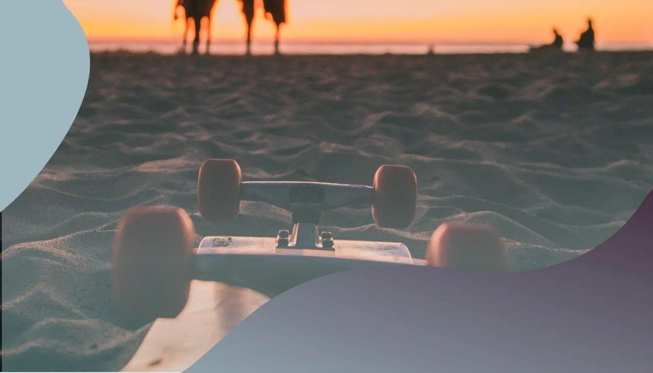 Am Strand liegt ein Skateboard mit Palmen und Sonnenuntergang im Hintergrund.