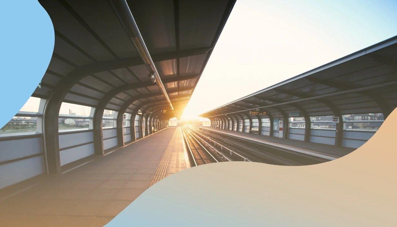 Futuristisch sanft geschwungene Überdachung einer Zughaltestelle mit starken Sonnenlichtreflexen.