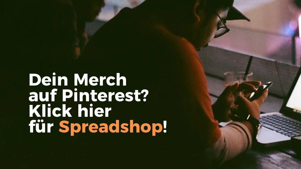 Person sitzt an einem Tisch mit Laptop vor sich und hält sein Smartphone vor sich.