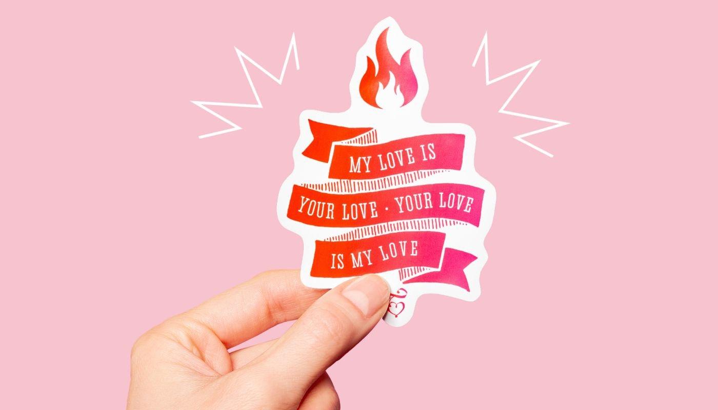 a hand holding a love-themed sticker made using spreadshop customization tools 