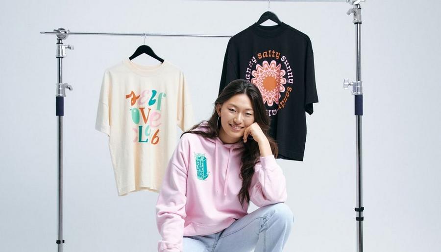 seller wearing custom hoodie with custom t-shirts behind them to illustrate how to price products