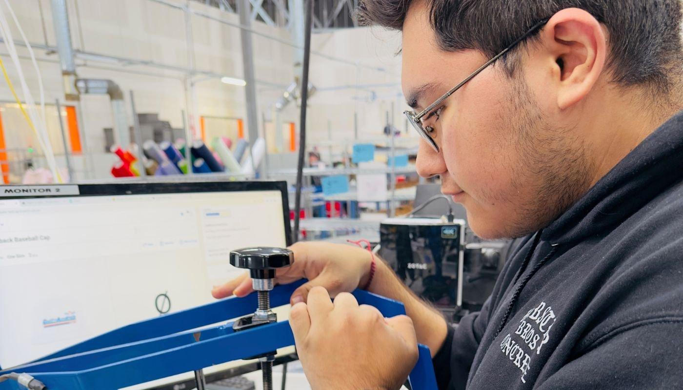Spreadshirt employee adjusting production equipment while preparing apparel inside the Las Vegas facility.
