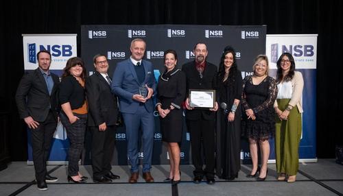 A group of Spreadgroup team members posing together after receiving a 2025 business award on stage.