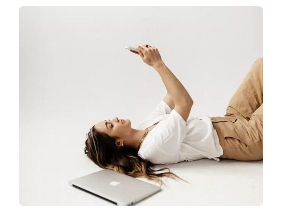 woman checking her phone with a laptop next to her to illustrate payment process
