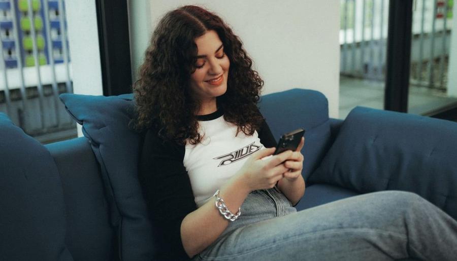 seller sitting on couch on phone to illustrate how to track print on demand earnings