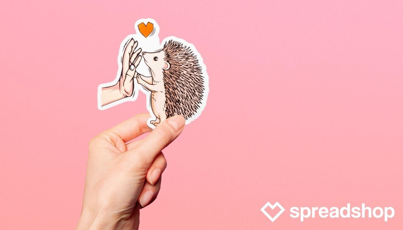 Cute Valentine’s Day hedgehog heart sticker design being held up by seller