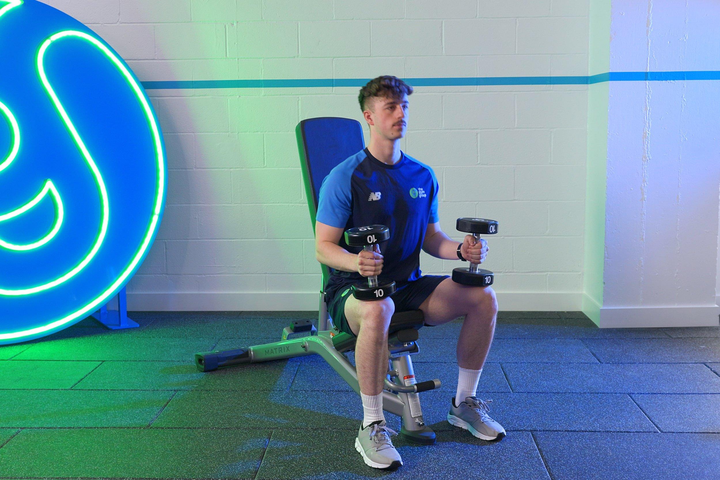 PT demonstrating how to set up a dumbbell shoulder Press.