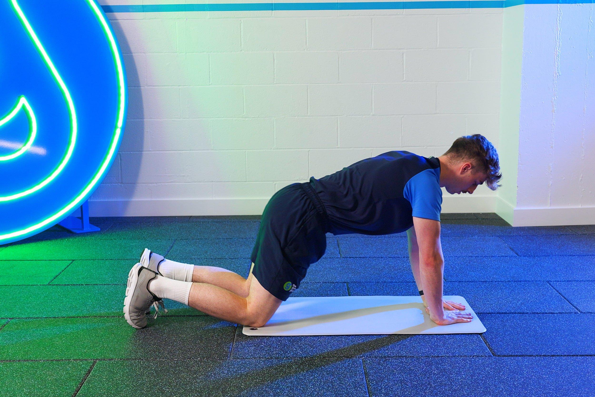 The Gym Group trainer demonstrating the tabletop starting position for a diamond push-up.
